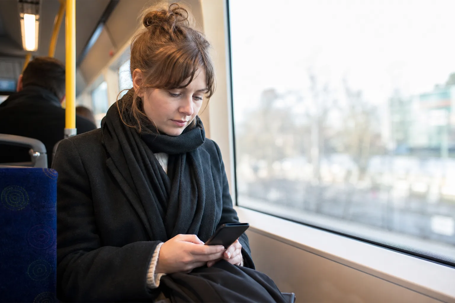 Pendlare på buss som använder mobilen på språng – mobildata går främst åt utanför wifi